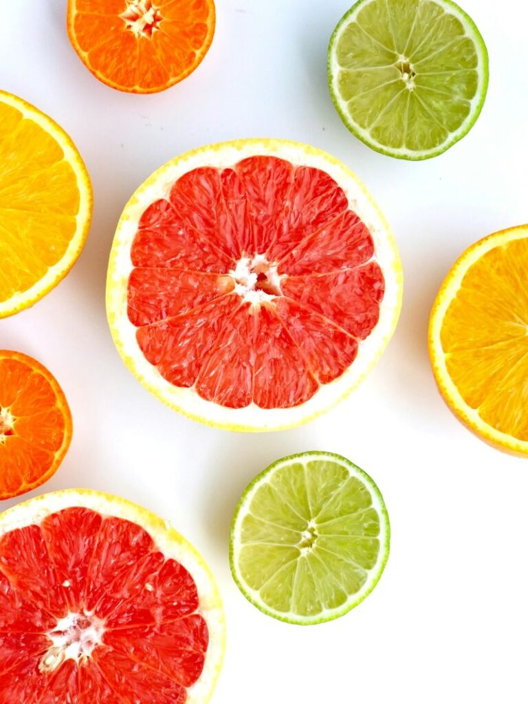 7 Hormone-Friendly Snacks Every Busy Mum Should Keep in Her Fridge | How to be a Mother y no Morir en el Intento Bright citrus slices of grapefruit, lime and orange on a white background used to illustrate how vitamin C boosts iron absorption in hormone-friendly snacks.